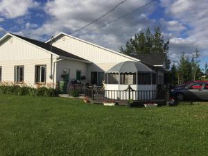 una casa blanca con cenador en un patio en Maison du Moulin en L'Isle-aux-Coudres