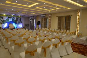 a banquet hall with white chairs and tables with bows at Hotel Muthahalli Grand in Bangalore