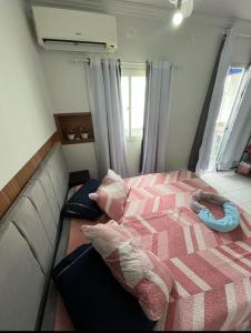 a bedroom with a bed with a pink comforter at Bela vista jardim camburi in Vitória