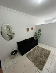 a living room with a black couch and a mirror at Bela vista jardim camburi in Vitória