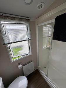a bathroom with a shower and a toilet and a window at Chesil View in Wyke Regis +19 photos