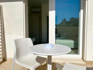 a white table with two chairs and a cup on it at Sea Rooms - Torre Pali in Torre Pali +14 photos