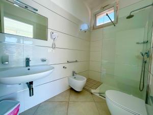 a white bathroom with a sink and a toilet at Sea Rooms - Torre Pali in Torre Pali