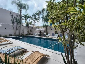a pool with chairs and palm trees next to a building at Das Nações Hotel in Florianópolis