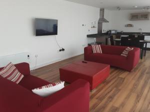a living room with two red couches and a tv at Elegant three bedroom flat in Darlington