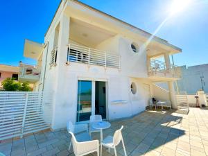 a white house with a table and chairs at Sea Rooms - Torre Pali in Torre Pali