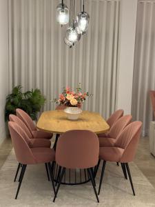 a dining room table with pink chairs and a vase of flowers at Odivelas Place 1 in Odivelas
