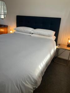 a large white bed with a blue headboard and a table at Cozy, Modern, Quiet House in Westport