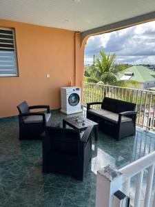 a porch with couches and tables and a balcony at Le Papillon in Le Moule