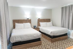 a hotel room with two beds with white sheets at Sunrise Motel in Owen Sound