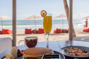 a table with a plate of food and a glass of orange juice at Alquimia Hotel Boutique in Tulum