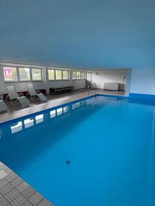 a large swimming pool in a building with chairs at MeLou FeWo NaturQuartier Wellness in Bad Lauterberg