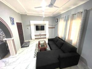 a living room with a black couch and a tv at Happy Home in Weija