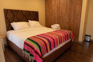 a bedroom with a bed with a colorful blanket on it at Hotel Campestre Rancho La Lechería in Cali