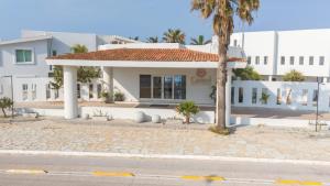 a white building with a palm tree in front of it at HOTEL CARASOL VILLAS & SUITES in Ciudad Madero