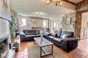 a living room with leather furniture and a stone wall at La Rochere in Sampzon
