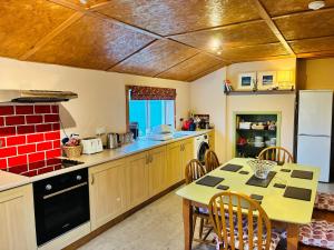 a kitchen with a table and chairs and a red brick at Pabbay House in Back