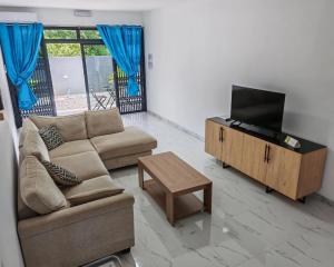 a living room with a couch and a flat screen tv at Label résidence 2 in Grand-Baie