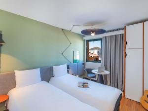 a hotel room with two white beds and a desk at Hotel ibis Evora in Évora +82 photos