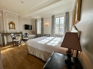 a hotel room with a bed and a table with a lamp at Hotel Du Midi in Visan