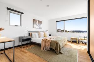 a bedroom with a bed and a desk and windows at The Lookout, Albany Holiday House in Albany