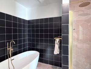 a bathroom with a tub and black tiles at The Revival House in Adams +18 photos