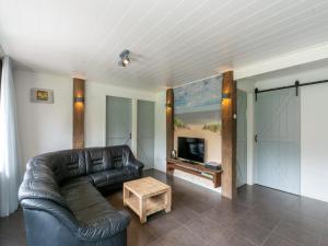 a living room with a leather couch and a television at Bungalow near Dutch Coast with Private Garden in Callantsoog