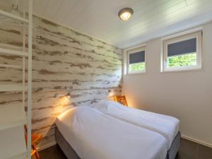 a bedroom with a white bed and a stone wall at Bungalow near Dutch Coast with Private Garden in Callantsoog