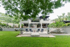 a white house with chairs in a yard at Villa De Vida Luxury Accomodations in Tangolunda