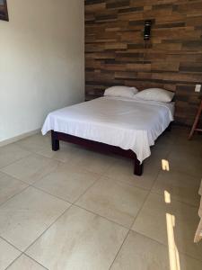 a bedroom with a bed with white sheets and pillows at Casa Pelícanos playa de chachalacas in Ursulo Galván