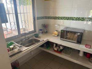 a kitchen with a sink and a microwave at Casa Pelícanos playa de chachalacas in Ursulo Galván