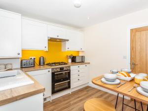 a kitchen with white cabinets and a wooden table at Court Terrace in Ripon +17 photos