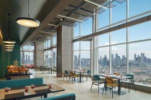 a restaurant with tables and chairs and large windows at Aloft by Marriott Jakarta Kebon Jeruk in Jakarta