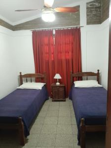 two beds in a room with a red curtain at Pura Brisa in Almafuerte