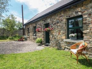 a stone house with a chair in front of it at Bohan Bo in Kilmuckridge
