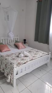 a bedroom with a white bed with a floral bedspread at Villa les Alizés in Les Anses-dʼArlets