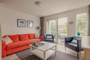 a living room with a orange couch and two chairs at Hollumerstrand in Hollum