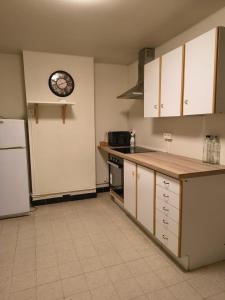 a kitchen with white cabinets and a clock on the wall at Namur cozy apartment in Namur