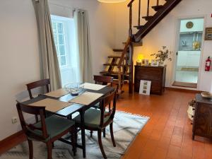 a dining room with a table and chairs and stairs at Casa da Torre in Porto Moniz