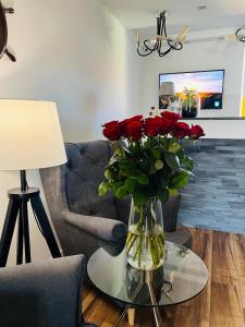 a vase with red roses on a table in a living room at MiraMar - Parking, wi-fi, Kuchnia ogólnodostępna in Krynica Morska