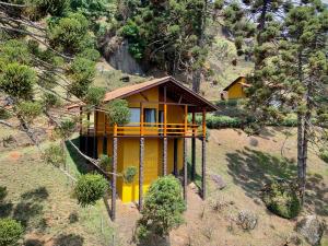 a small yellow house on the side of a hill at Pousada Toca da Onça in Gonçalves +84 photos