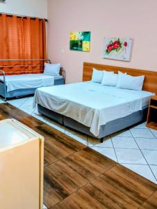 two beds in a room with wood floors at Calabreza Hotel e Restaurante in Três Corações