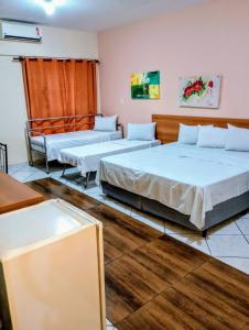 two beds in a room with wooden floors at Calabreza Hotel e Restaurante in Três Corações