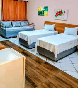 two beds and a couch in a room at Calabreza Hotel e Restaurante in Três Corações