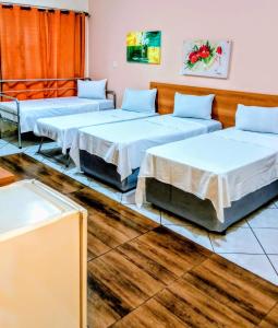 three beds in a room with wooden floors at Calabreza Hotel e Restaurante in Três Corações +30 photos
