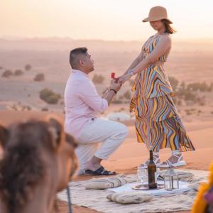 a man and a woman standing on a table in the desert at Sand Dunes Luxury Camp in Merzouga
