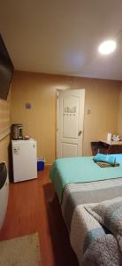 a room with two beds and a refrigerator and a door at Turismo FORTALEZA PATAGONIA in Puerto Natales