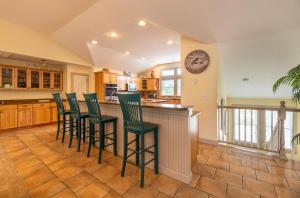 a kitchen with green bar stools at a counter at Beach Cabana - Southern Shores, 6 En-Suites, Elevator, Pool, Cabana Bar, Hot Tub, Game Room in Southern Shores