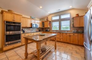 a large kitchen with wooden cabinets and a wooden table at Beach Cabana - Southern Shores, 6 En-Suites, Elevator, Pool, Cabana Bar, Hot Tub, Game Room in Southern Shores