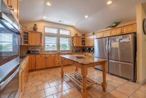 a kitchen with wooden cabinets and a stainless steel refrigerator at Beach Cabana - Southern Shores, 6 En-Suites, Elevator, Pool, Cabana Bar, Hot Tub, Game Room in Southern Shores +76 photos